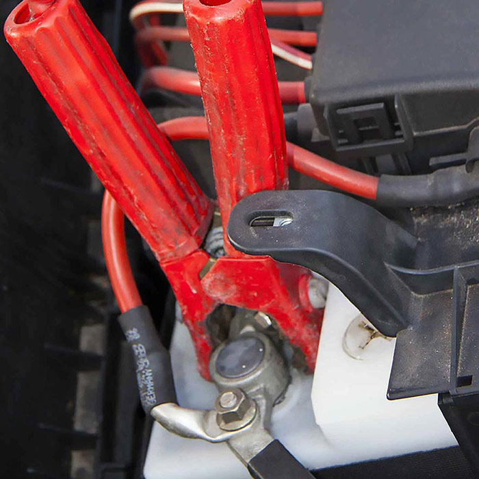 roadside-battery-jump-start-service Battery with jumper cables connected for a roadside jump start service to get a dead car battery running again.